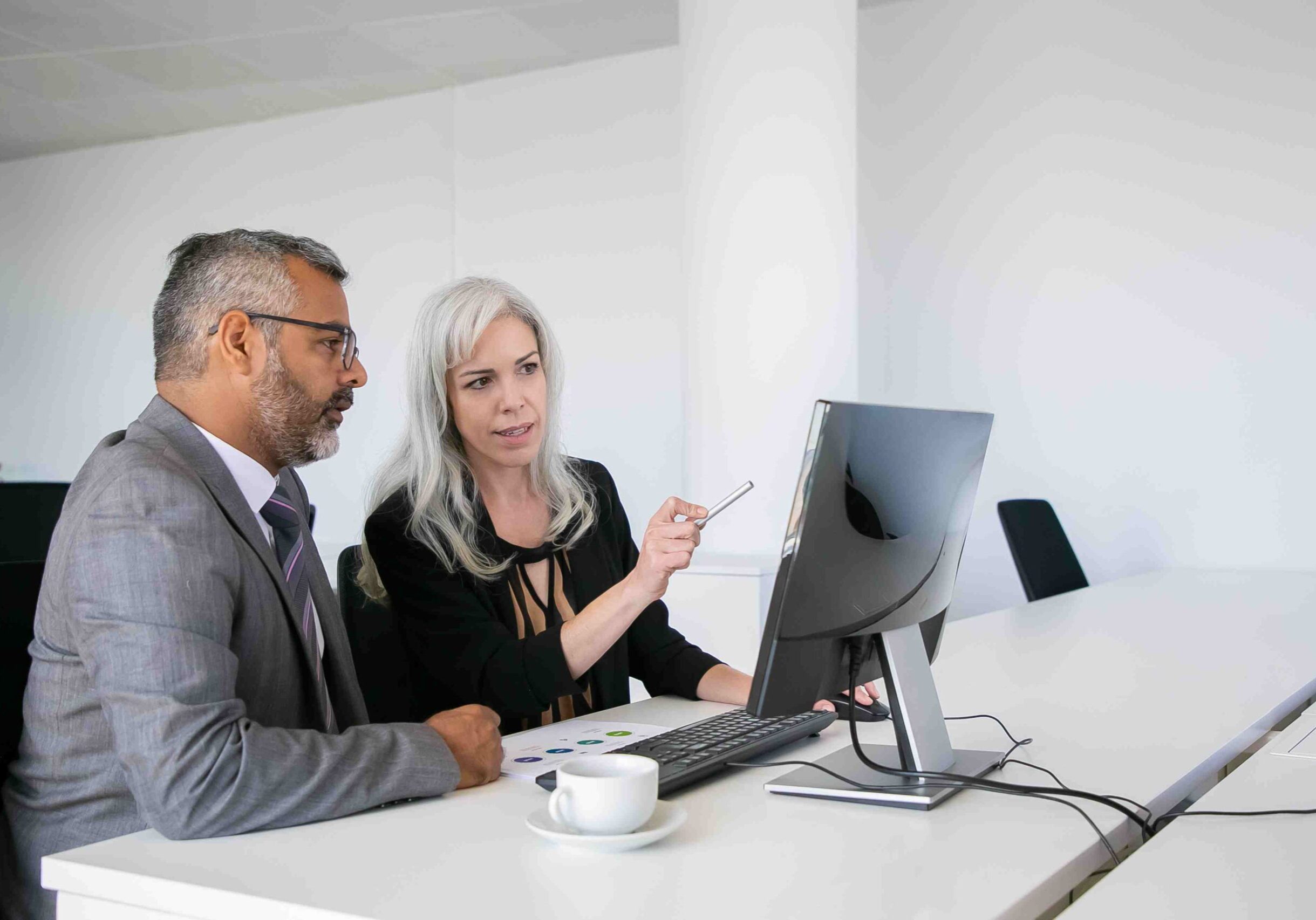 focused-business-colleagues-watching-content-computer-pointing-display-talking-while-sitting-desk-with-paper-chart-business-communication-concept_11zon